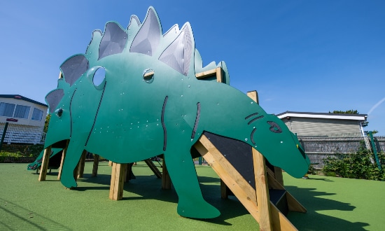 Wooden green stegosaurus featuring steps and a slide