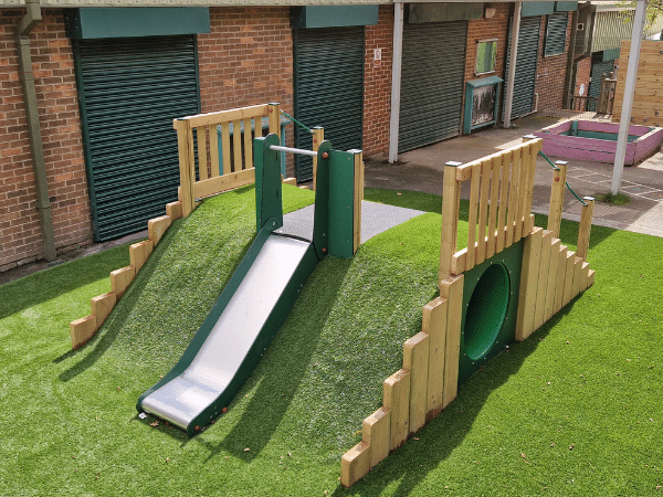 Outdoor Play Mound Tunnel with Slide into artificial grass at primary school