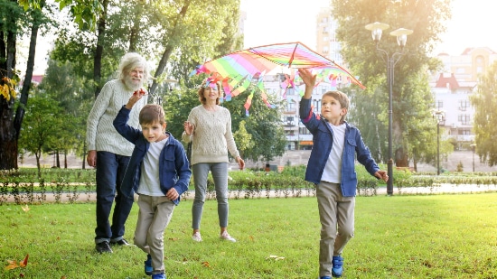 Older couple and two children in the park flying a multicoloured kite