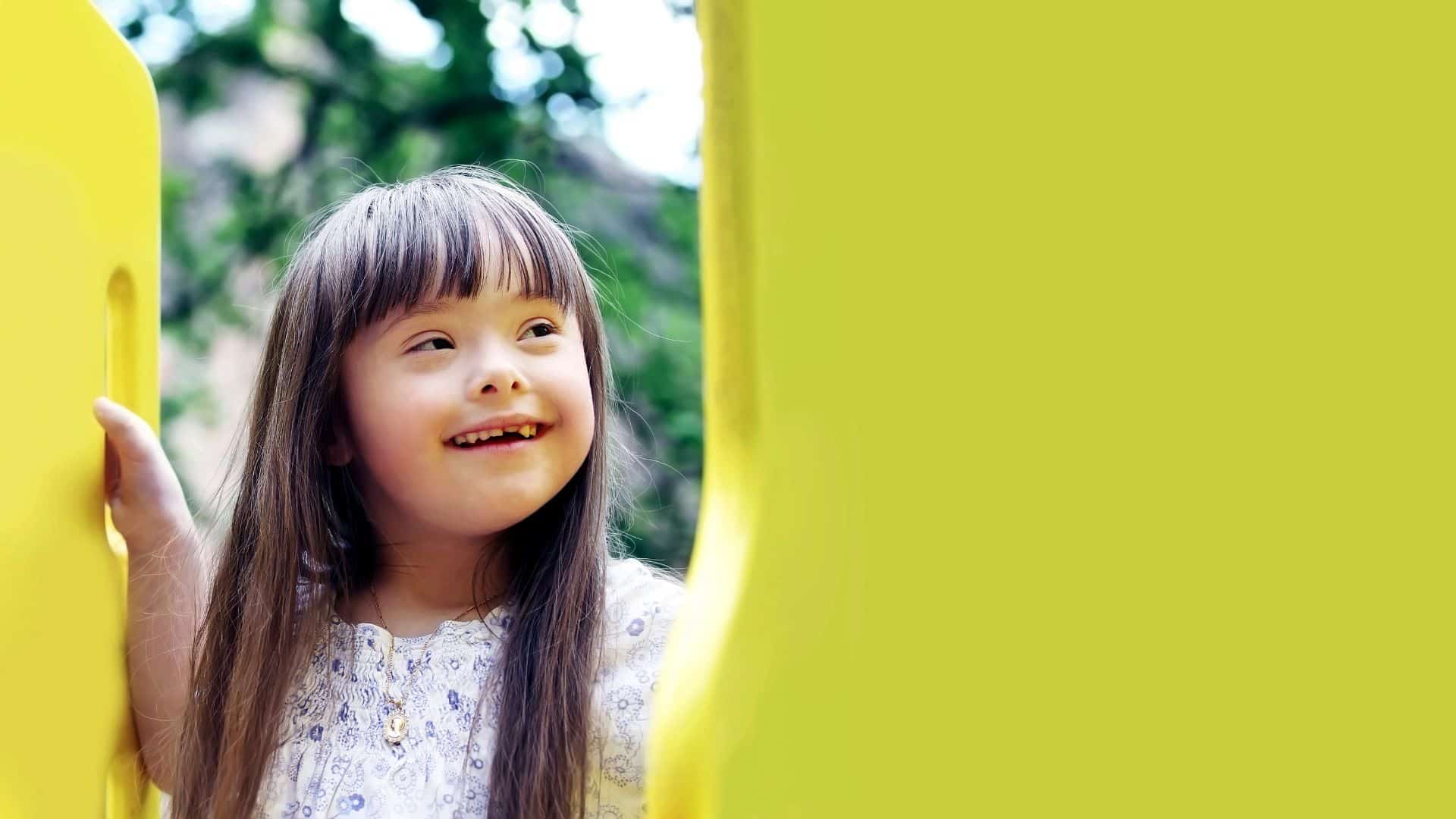 A little girl peering inbetween two lime green panels at a playground