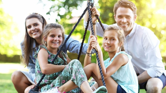 Family posing for a photo on a swinger outdoors
