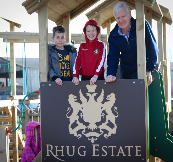 Older man stood on a play tower with two young boys 