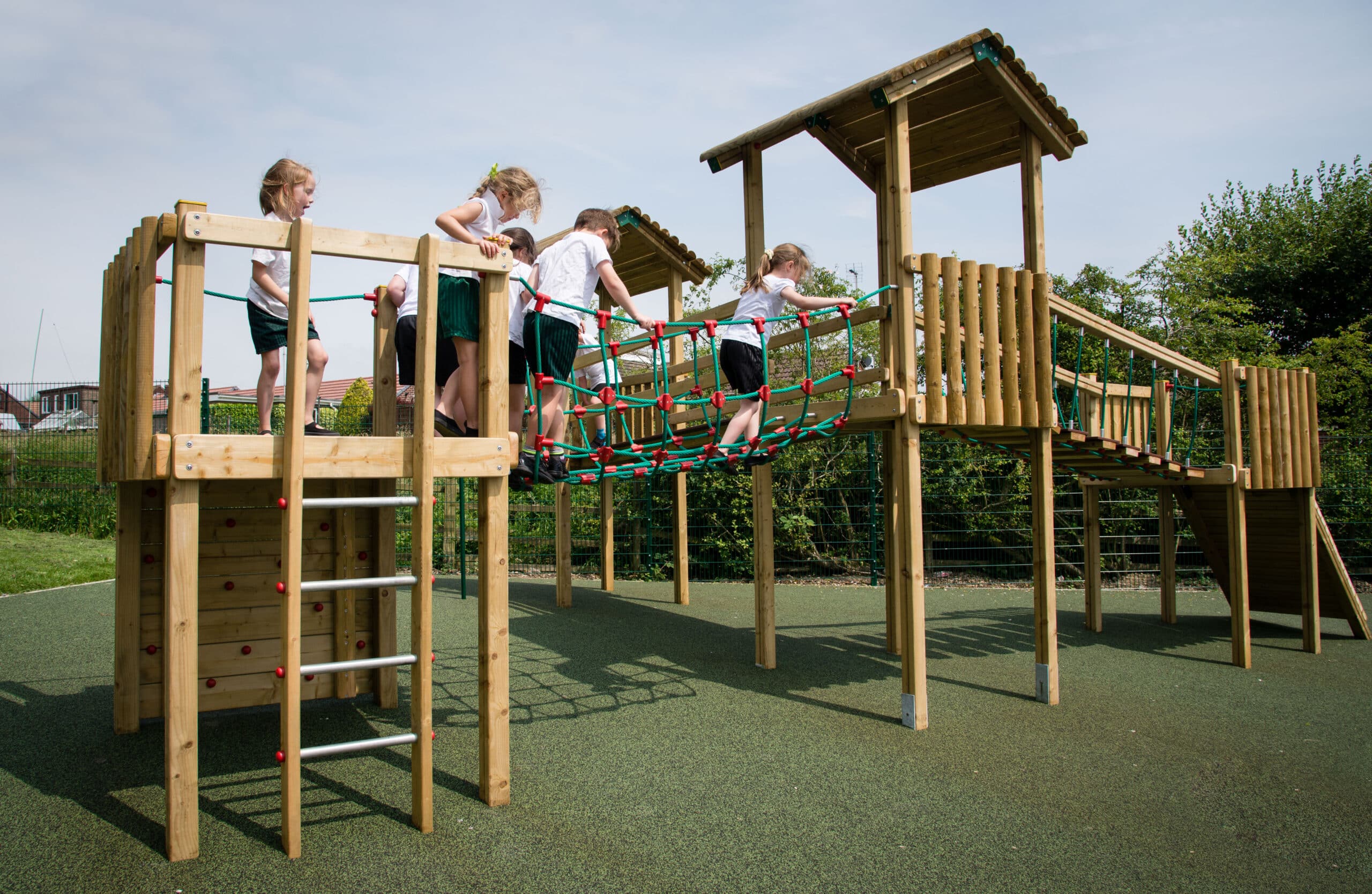 Four children in school uniforms cross a rope bridge on a playground tower