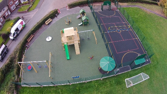 Aerial view of outdoor play area featuring a wooden tower and a ball game area