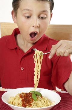 Boy in red top excited at eating pasta