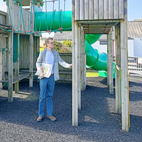An inspector assesses the quality of a wooden play tower by touching it