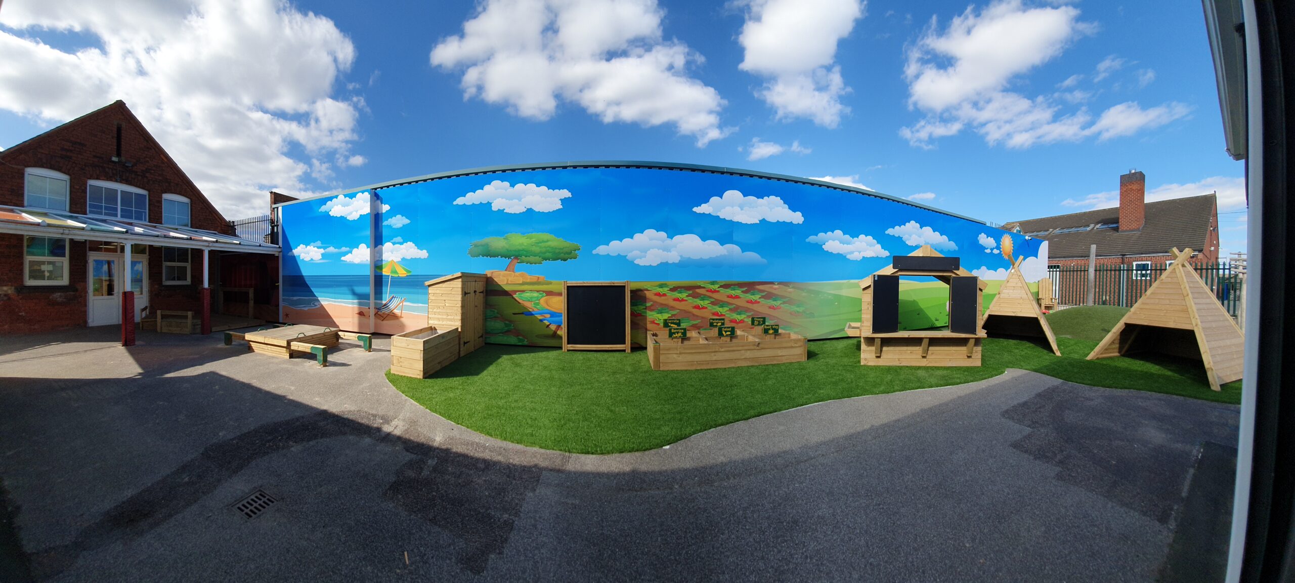 Nursery playground featuring several timber structures in front of a painted sky backdrop