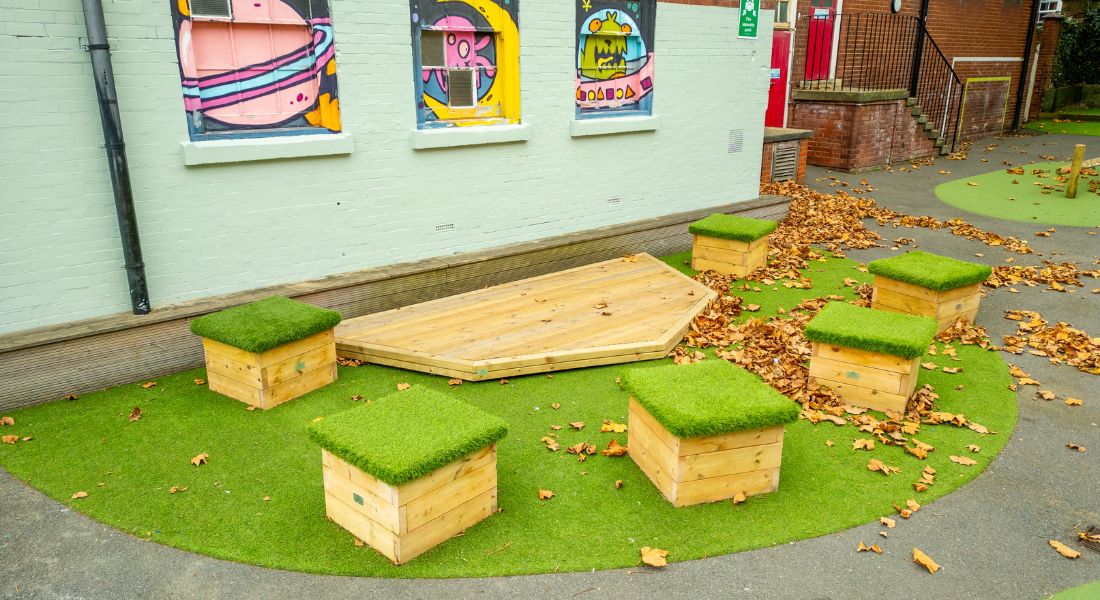 outdoor stage with grass-topped seating at a school playground