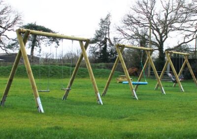 Two wooden-structure swings set on grass
