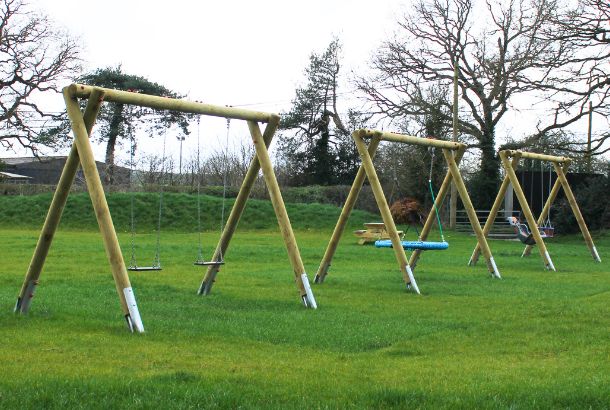 Two wooden-structure swings set on grass