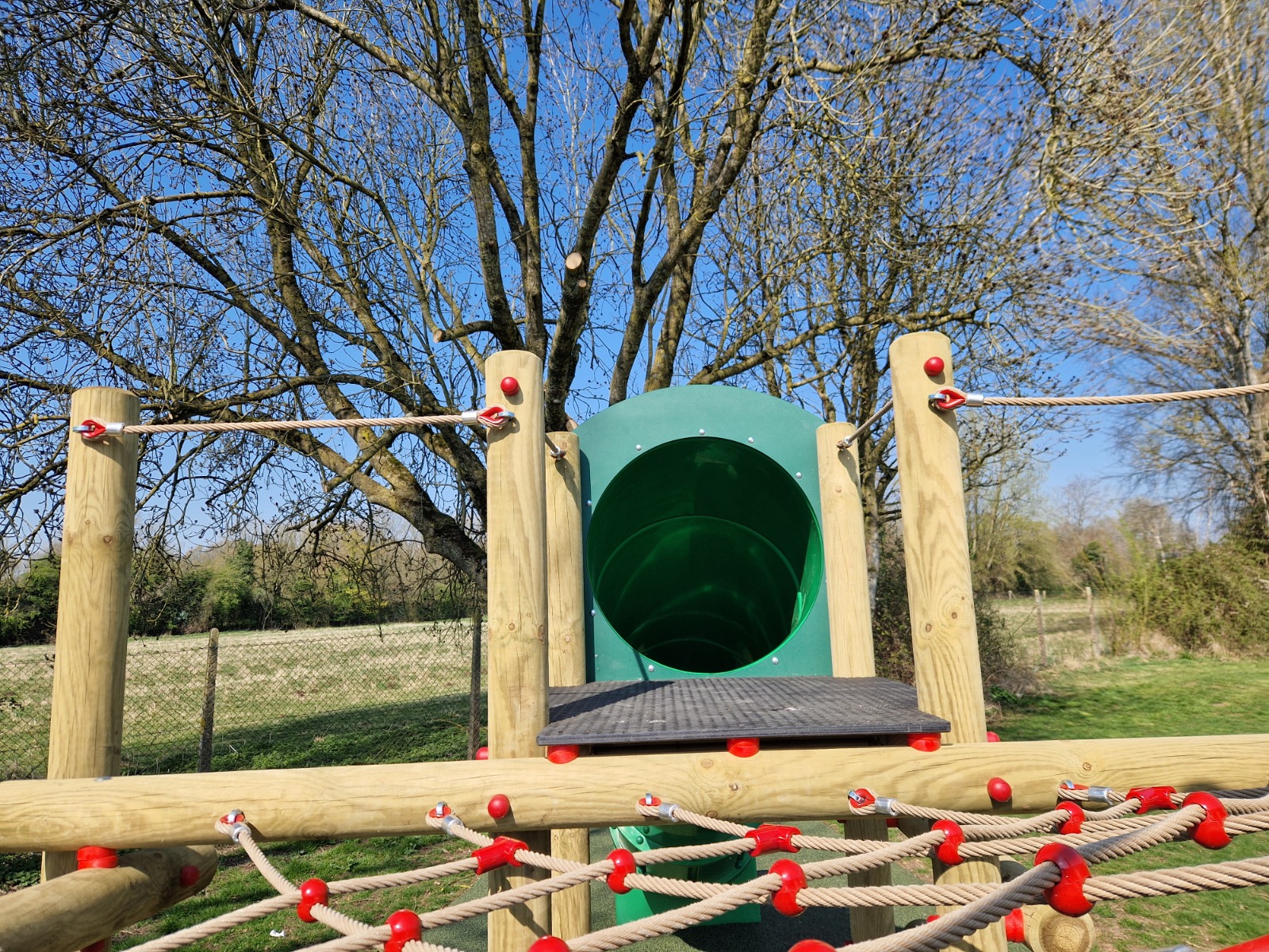 Entrance to a green tube slide at a playground