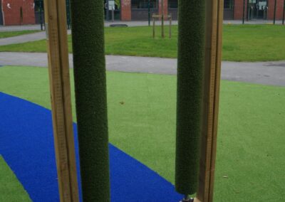 Green rollers sat vertically on a blue path in a grassy area
