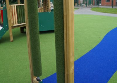 Green rollers sat vertically on a blue path in a playground