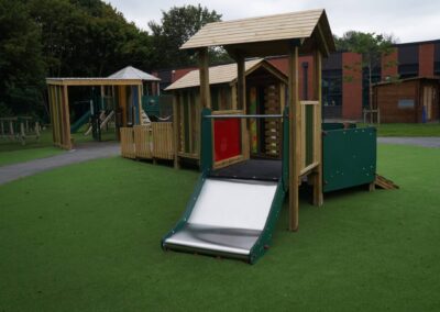 Wide metal slide which is part of a timber play tower at a playground