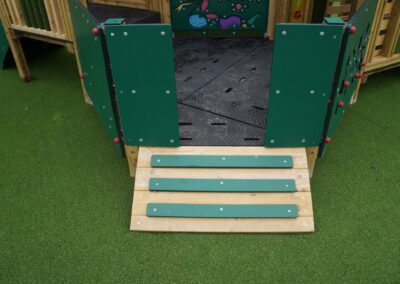 Short ramp structure with footholds leading up a timber play tower