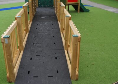 Ramp entrance to a timber play tower at a grass playground