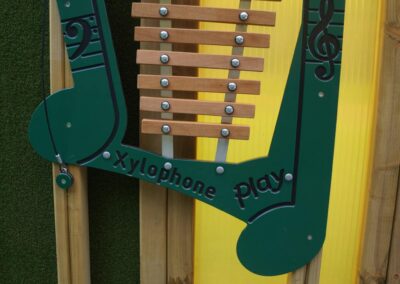 Green panelled Playground glockenspiel sat against a multi-coloured background