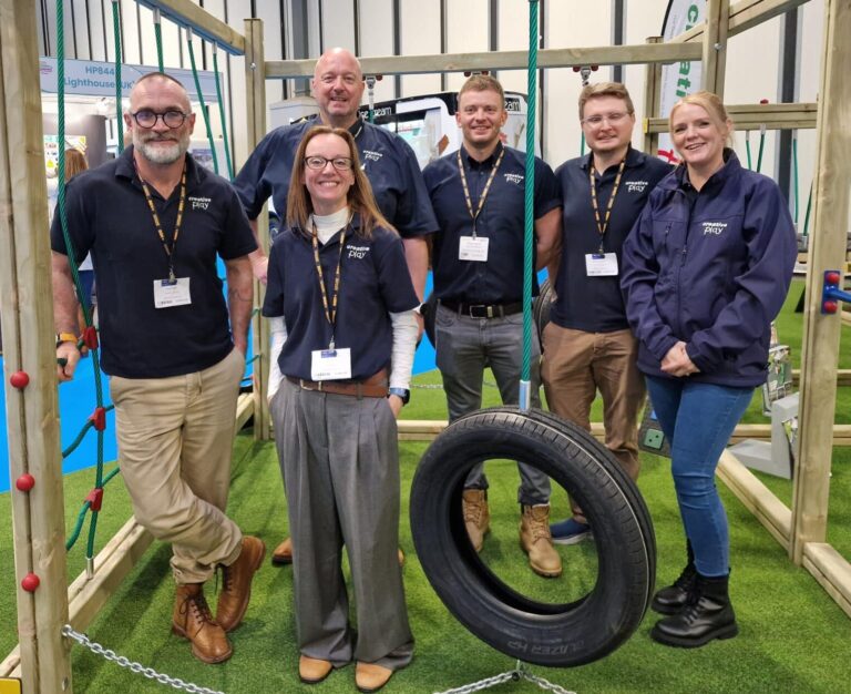 Group of employees stood around timber play equipment at a trade event