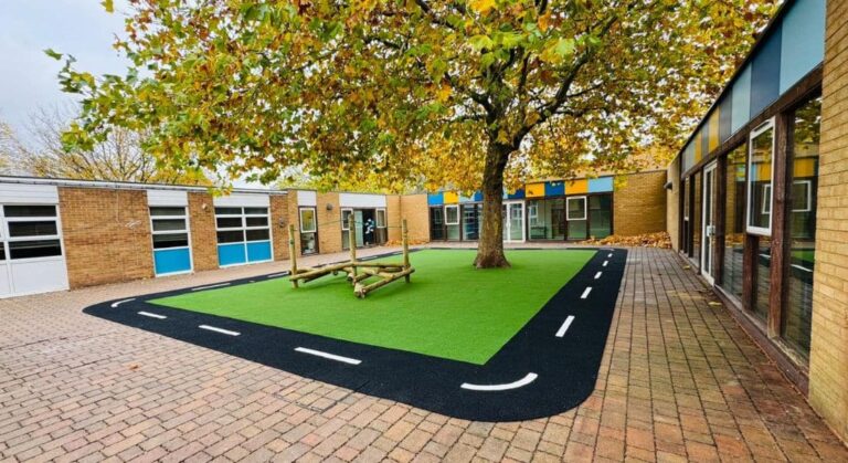 Pictured is a Jungle Climber Explorer with pile green multi-play artificial grass safety surfacing including artificial grass roadway