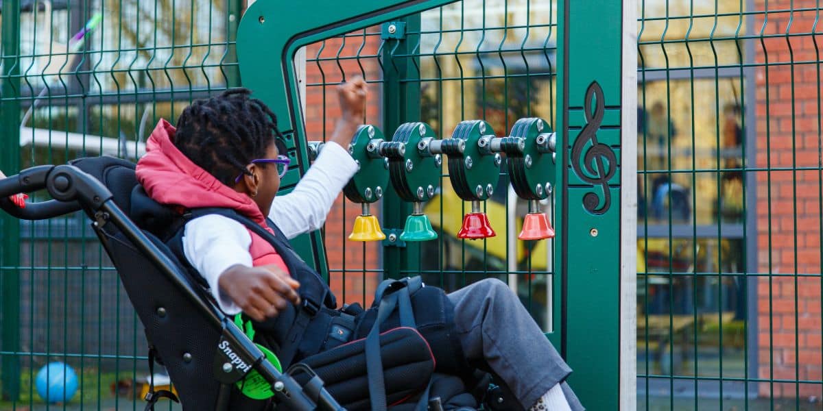 This image shows a female pupil in a wheel chair playing with the musical bell board