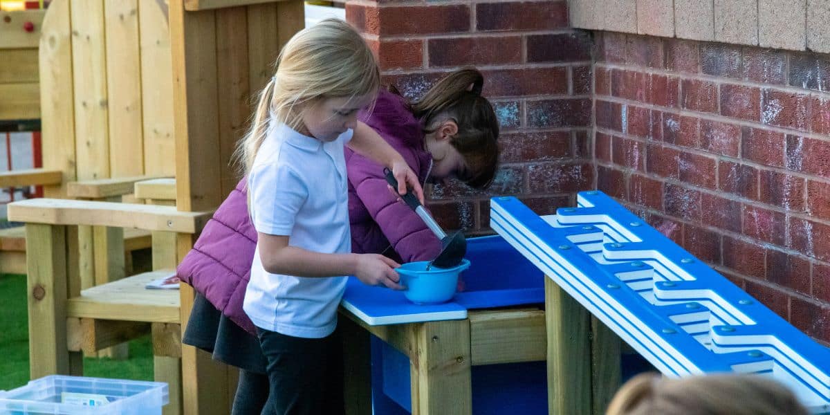 Pictured are two pupils playing with sensory outdoor playground equipment