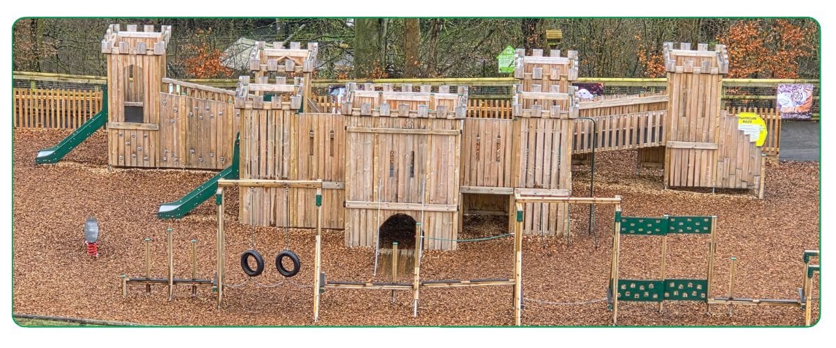 Windsor castle and an adventure trail both made of timber sat on a ground of bark chippings in a wooded area