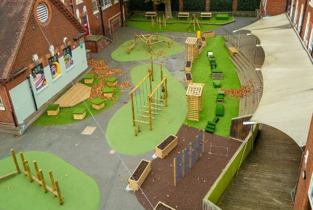 Wide selection of round timber outdoor play equipment on green surfacing at South Harringay School