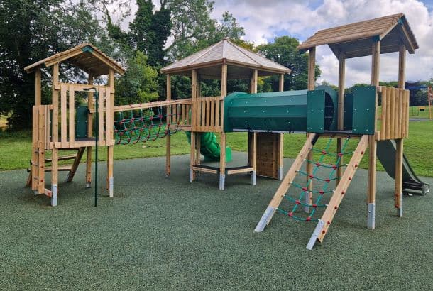 Three tower timber structure on safety surfacing in play park in West Meon