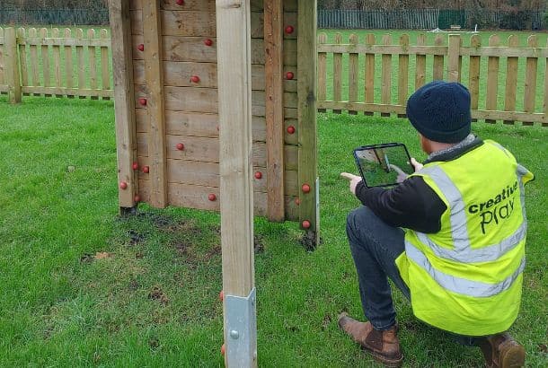 This image shows a Creative Play team member conducting a inspection of a playground in the UK