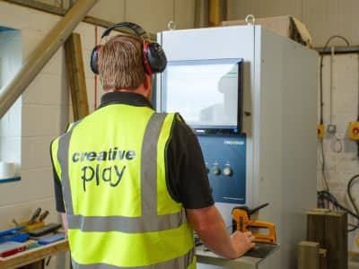 This image shows a Creative Play factory worker using the CNC cutting machine