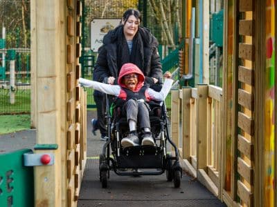 This image shows a female pupil who uses a wheelchair enjoying the dragon fly jigsaw tower from Creative Play