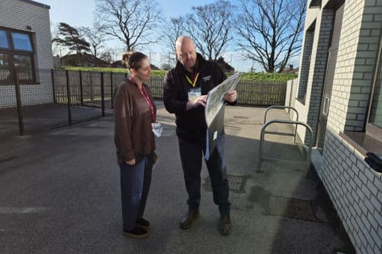 Man explaining something to a woman in a yard with aid of a paper document