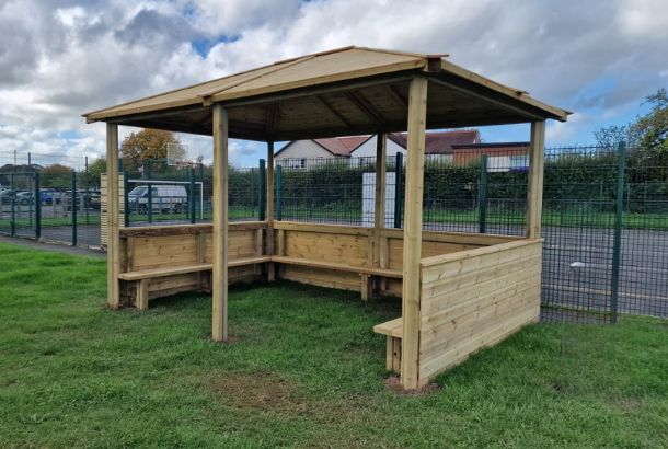 This image shows a hipped roof shelter on grass