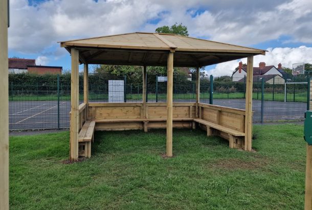 This image shows a hipped roof shelter on grass