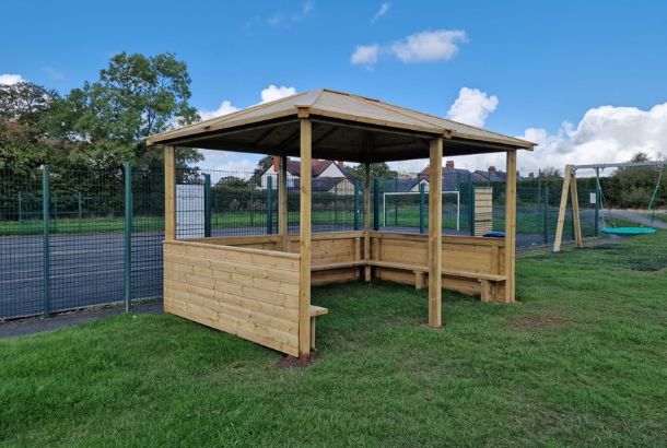 This image shows a hipped roof shelter on grass