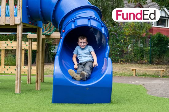 This image shows a young boy in a school uniform coming down a slide with the FundEd Logo in the top right hand corner 