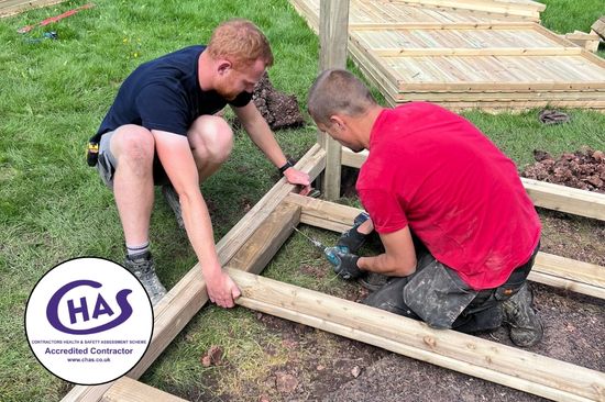 This image shows two male playground contractors working on a playground building site.