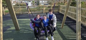 Three children sharing a basket swing
