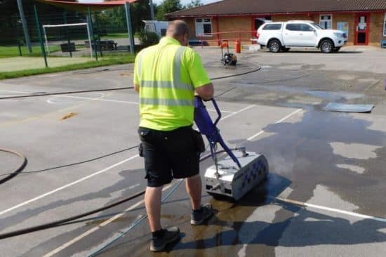 This image shows a male worker jet washing a playground