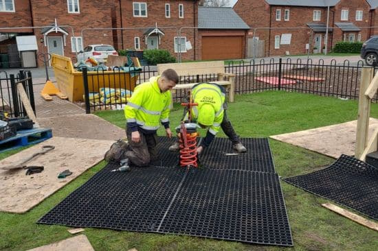 This image shows two male workers repairing existing playground equipment