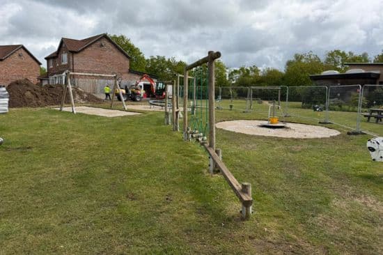 This image shows a male construction team on site in on a housing estate in the UK building a new playground  area
