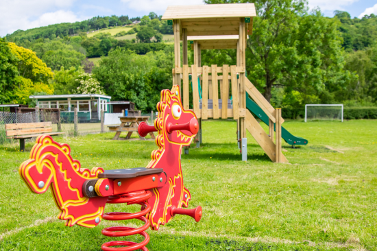 This image shows a red dragon spring rider and a jigsaw tower in a local authority playground 