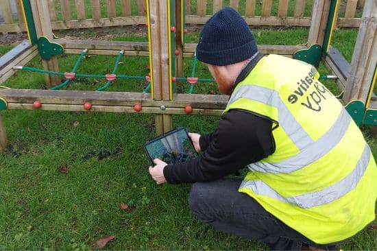This image shows a male playground inspector conducting an inspection