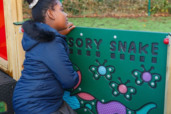 This image shows a black female pupil playing with a sensory snake play board 