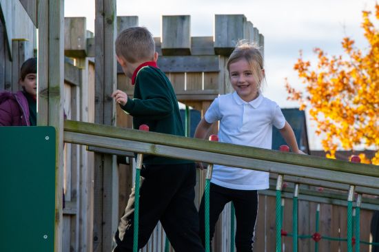 New Website Imagery - KS1 & KS2 (7) This image shows a male and female pupil walking along a play tower bridge in school uniform