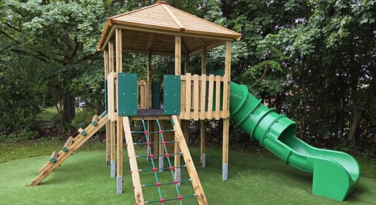 This image shows a bespoke single wooden jigsaw tower with slide and climbing rope on artificial grass