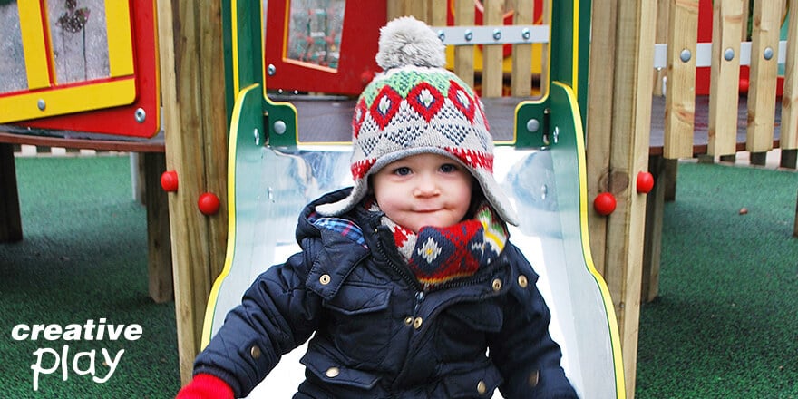 Child on slide wearing colourful hat