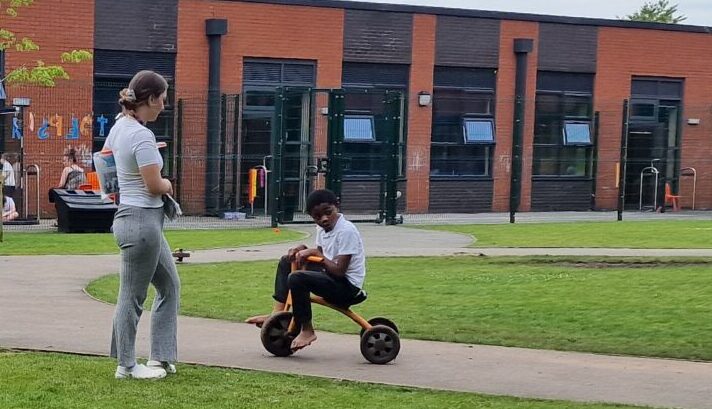 Small boy on a plastic trike riding along playground route 