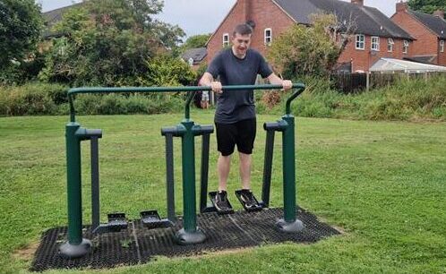 A mentally impaired man learns to use outdoor metal gym equipment in a playground