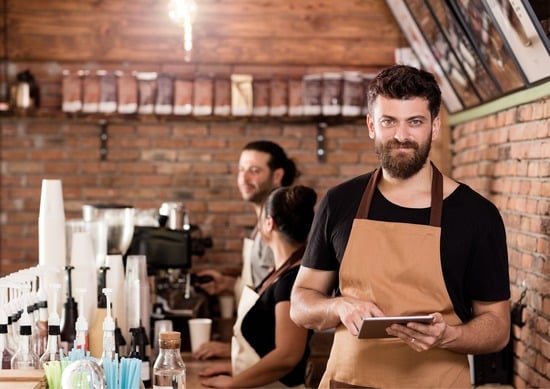 Barista takes order on an ipad as other staff stand around chatting